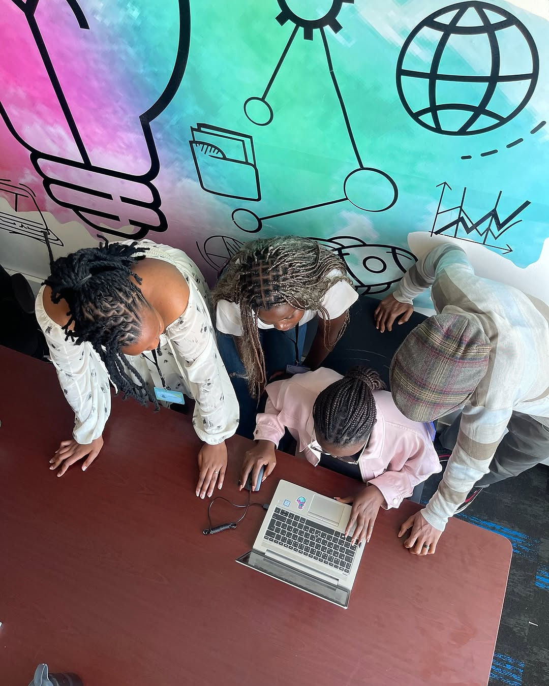 Impact Outsourcing reviewers huddled at a laptop during a rubric calibration session.